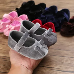 Detailansicht von grauen Samt-Babyschuhen mit dekorativer Schleife und weicher Sohle