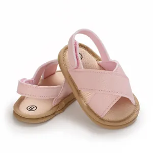 Vista detallada de sandalias rosas para bebé con suela blanda y diseño cruzado