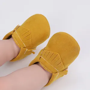Nahaufnahme von gelben Wildleder-Babyschuhen mit Fransenverzierung und weicher Sohle.