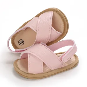 Primer plano de sandalias rosas para bebés con correas cruzadas y suelas blandas
