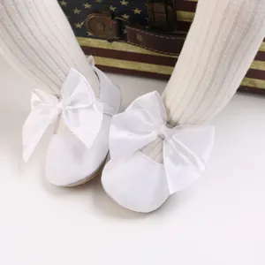 Gros plan de chaussures de princesse bébé blanches avec nœuds en satin sur collants