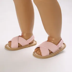 Primer plano de sandalias rosas para bebé con correas cruzadas en pie de maniquí