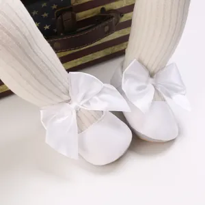 Vue détaillée de chaussures de princesse pour bébé blanches avec un grand nœud en soie