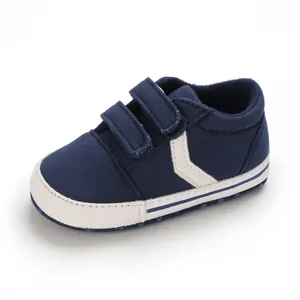 Vista detallada de zapatos de bebé azul marino con suela blanca blanda y cierre velcro.