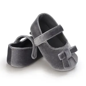 Nahaufnahme grauer Samt-Babyschuhe Mary Jane mit weichen Sohlen und Schleifenakzenten