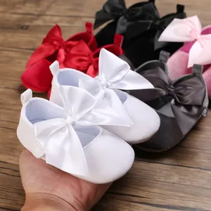 Gros plan d'une chaussure de princesse blanche pour bébé avec un grand nœud en satin