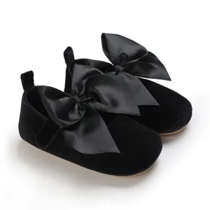 Détail de chaussures princesse bébé noires avec grand nœud en satin et semelle souple