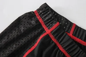 Detailed close-up of breathable mesh fabric and red stitching on men's cycling shorts