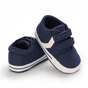 Vista detallada de zapatos de lona para bebé en azul marino con suela blanda y velcro.