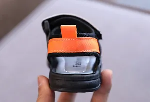 Detaillierte Makroansicht des Fersenriemens von Jungensandalen in Schwarz und Orange