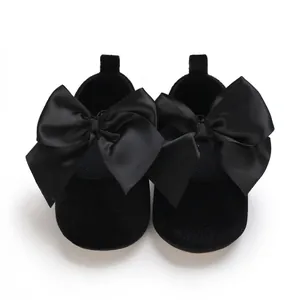 Vue détaillée de chaussures de princesse bébé noires avec nœuds en satin et semelle souple
