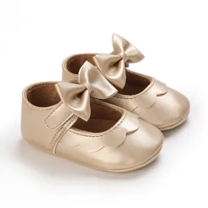 Nahaufnahme goldener Baby-Prinzessinenschuhe mit Metallic-Finish und Schleife