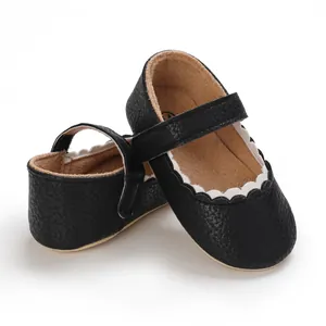 Makroansicht von schwarzen Baby-Lauflernschuhen aus Leder mit eleganten weißen Wellenkanten.