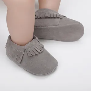 Nahaufnahme von grauen Wildleder-Babyschuhen mit Fransen