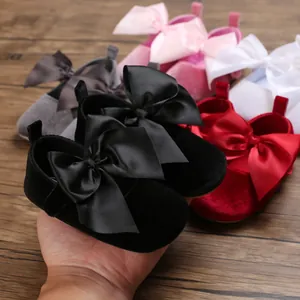 Détail de chaussures de princesse en velours pour bébé avec grands nœuds en satin