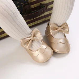 Detailaufnahme goldener Baby-Laufschuhe im Prinzessinnen-Stil mit einer Schleife.
