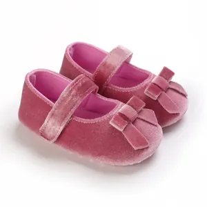 Detailaufnahme von weichen rosa Samt-Babyschuhen mit dekorativer Schleife und Riemen