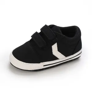 Primer plano de zapatillas de lona negra para bebé con suelas blancas suaves y velcro.