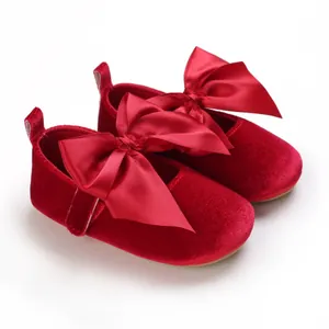 Vue détaillée de chaussures de princesse en velours rouge avec de grands nœuds.