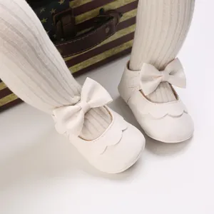 Detailansicht weißer Baby-Lauflernschuhe mit Schleife und Wellenrandverzierung
