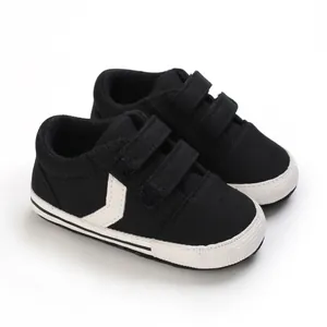 Vista detallada de zapatos de lona negra para bebé con correas de velcro blancas