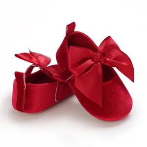 Détail de chaussures de princesse pour bébé en velours rouge avec grand nœud en satin.
