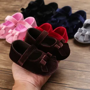 Nahaufnahme brauner Baby-Mary-Janes aus Samt mit einer Schleife und weicher Sohle.