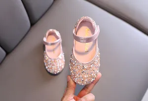 Close-up view of pink girl's dress shoes featuring sparkling rhinestones and pearls