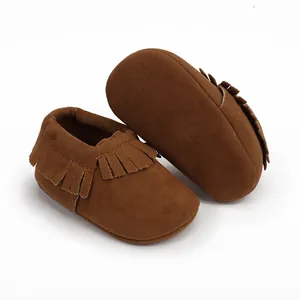 Detailaufnahme von weichen braunen Baby-Mokassins aus Wildleder mit modischen Fransen.