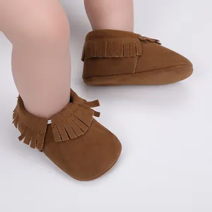 Detailansicht weicher brauner Baby-Mokassins aus Wildleder mit Fransenbesatz.