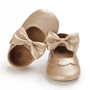 Detaillierte Nahaufnahme goldener Baby-Lauflernschuhe mit einer eleganten Schleife