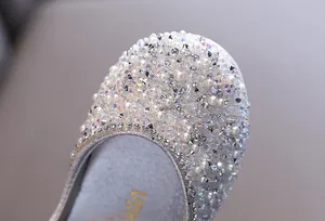 Close-up detail of glittering rhinestones and faux pearls on girls' silver dance shoes