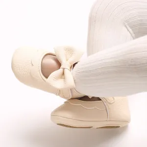 Close-up of cream baby girl princess shoes with leather bow detail and soft sole