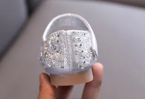 Detail view of sparkling rhinestone and pearl embellishments on silver girls' dance shoes.
