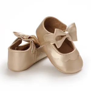 Nahaufnahme der goldenen Baby-Prinzessin-Schuhe mit Schleife und weicher Sohle.