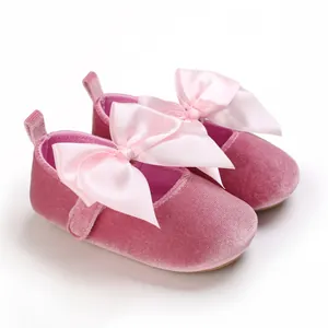 Vue détaillée de chaussures de princesse en velours rose pour bébé avec un grand nœud.