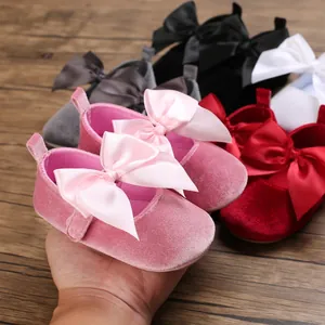 Gros plan sur des chaussures de princesse en velours rose pour bébé avec un gros nœud.