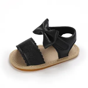 Vista laterale dettagliata del sandalo nero per neonata con fiocco in pelle su sfondo bianco