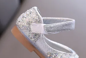 Close-up detail of sparkling silver rhinestones and faux pearls on a girl's dress shoe