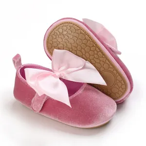 Vista detallada de zapatos de terciopelo rosa para bebé con un gran lazo de satén