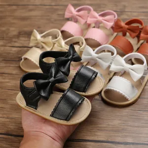 Primo piano di adorabili sandali per neonata con fiocco in vari colori su base di legno