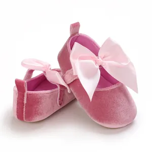 Gros plan de chaussures en velours pour bébé montrant la texture et le nœud en satin