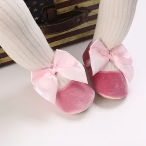 Détail de chaussures de princesse rose en velours pour bébé avec un grand nœud en satin