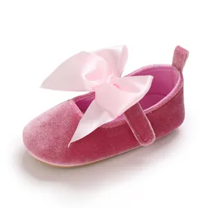 Vue détaillée de chaussure princesse bébé en velours rose avec un grand nœud en satin.