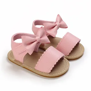 Dettaglio sandali rosa per neonata con grande fiocco decorativo e bordi smerlati