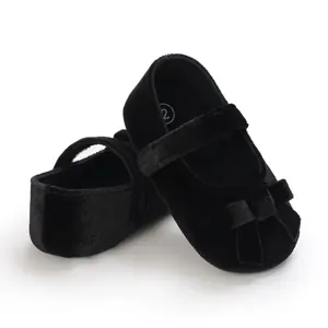 Nahaufnahme schwarzer Baby-Mary-Janes aus Samt mit Schleife und weicher Sohle