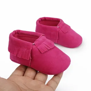 Detaillierte Makroansicht von rosa Wildleder-Babymokassins mit modischen Fransen