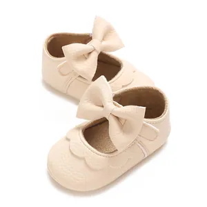 Close-up detail of cream baby walker shoes featuring a large bow and soft leather texture.