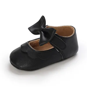 Close-up of black baby girl Mary Jane shoes with elegant bow and scallop trim