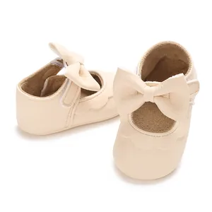 Close-up of cream baby girl princess shoes with large bow and soft rubber sole.